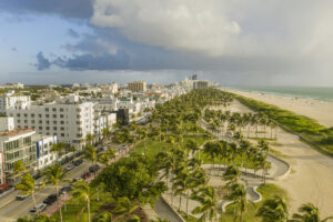 Fianzas en South Beach, FL: Una vista vibrante de sombrillas coloridas en la arena, con palmeras ondeando al fondo bajo un cielo azul claro.