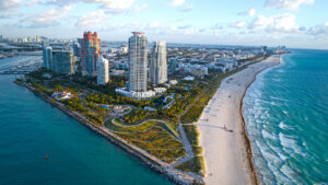 Fianzas en South Beach, FL: Una vista vibrante de sombrillas coloridas en la arena, con palmeras ondeando al fondo bajo un cielo azul claro.